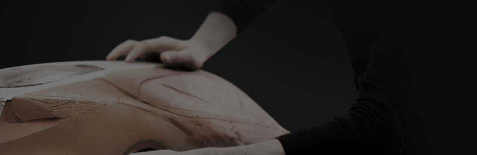 Closer view of hands polishing a clay model.